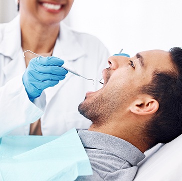 Man with black hair in grey shirt having dental exam